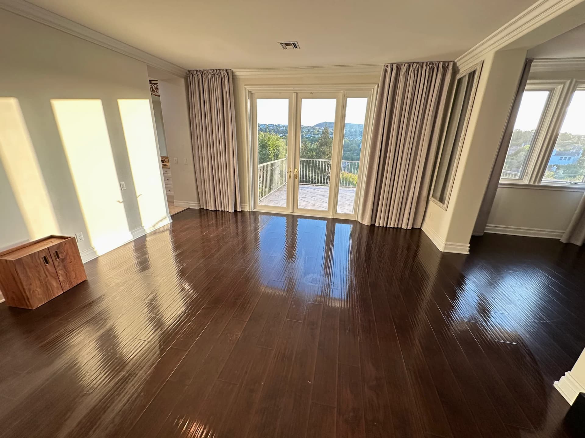 Empty room hardwood floors after LA Top Clean — polished glossy wood reflecting light by French doors