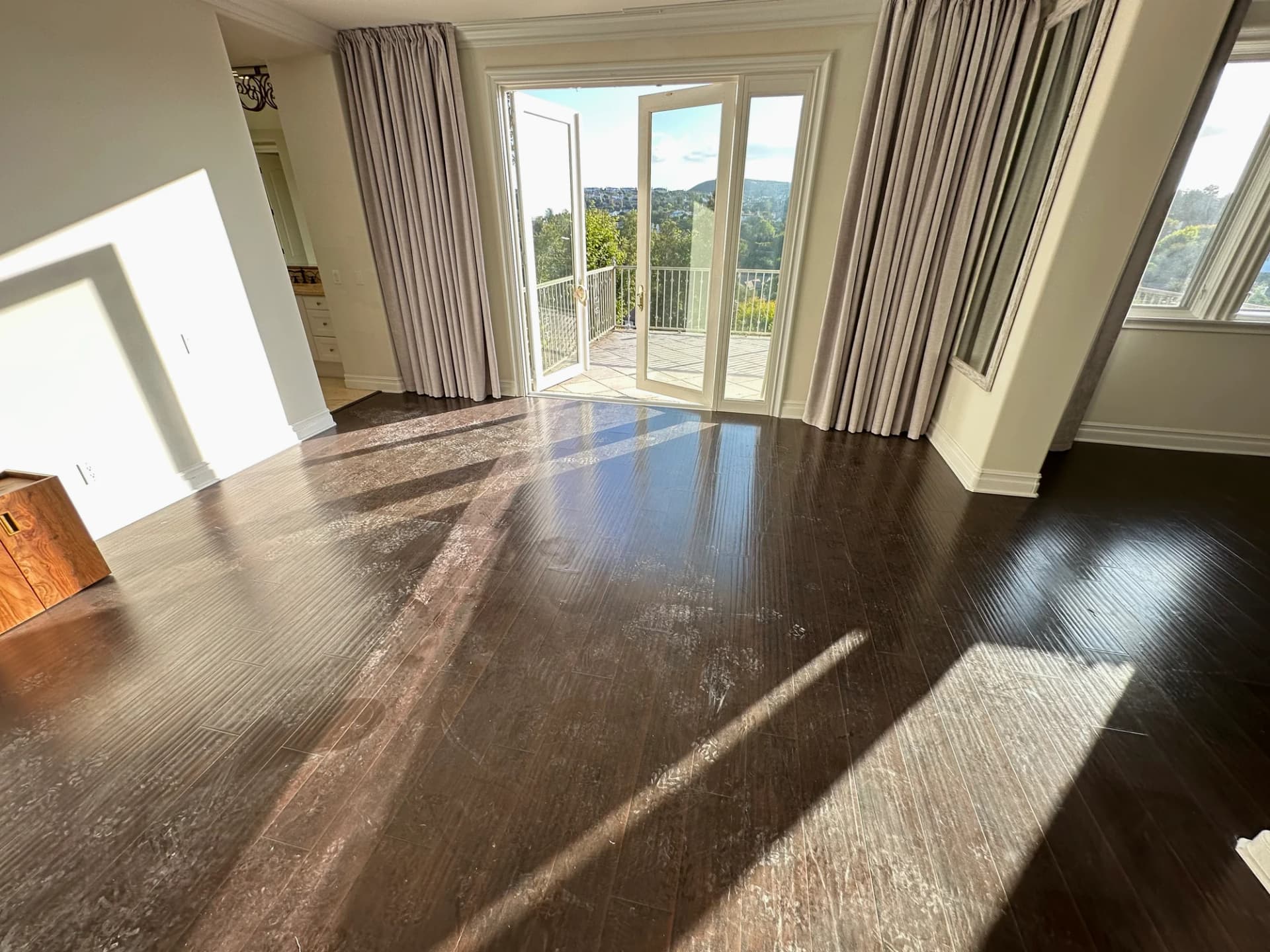 Empty room hardwood floors before cleaning — dusty and dull dark wood with visible haze