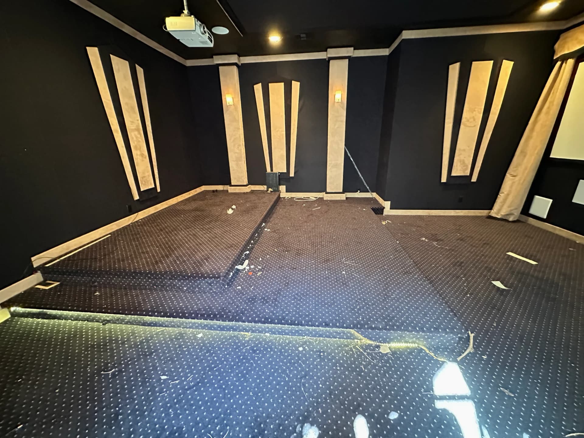Home theater room before cleaning — debris and dust on the carpeted platform and floor