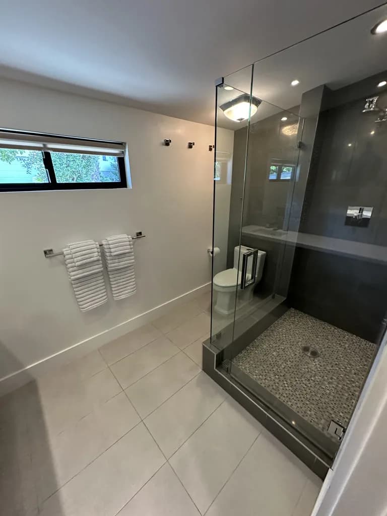 Modern bathroom with glass shower and marble tile floors after cleaning