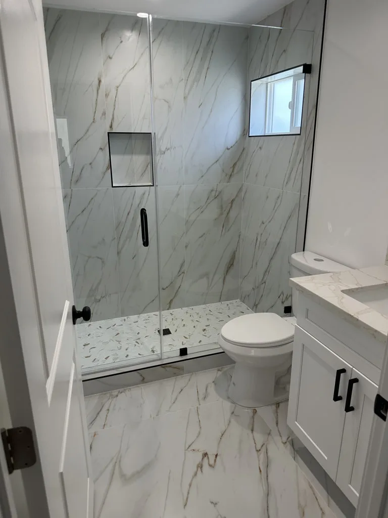 White marble bathroom with glass shower enclosure after cleaning