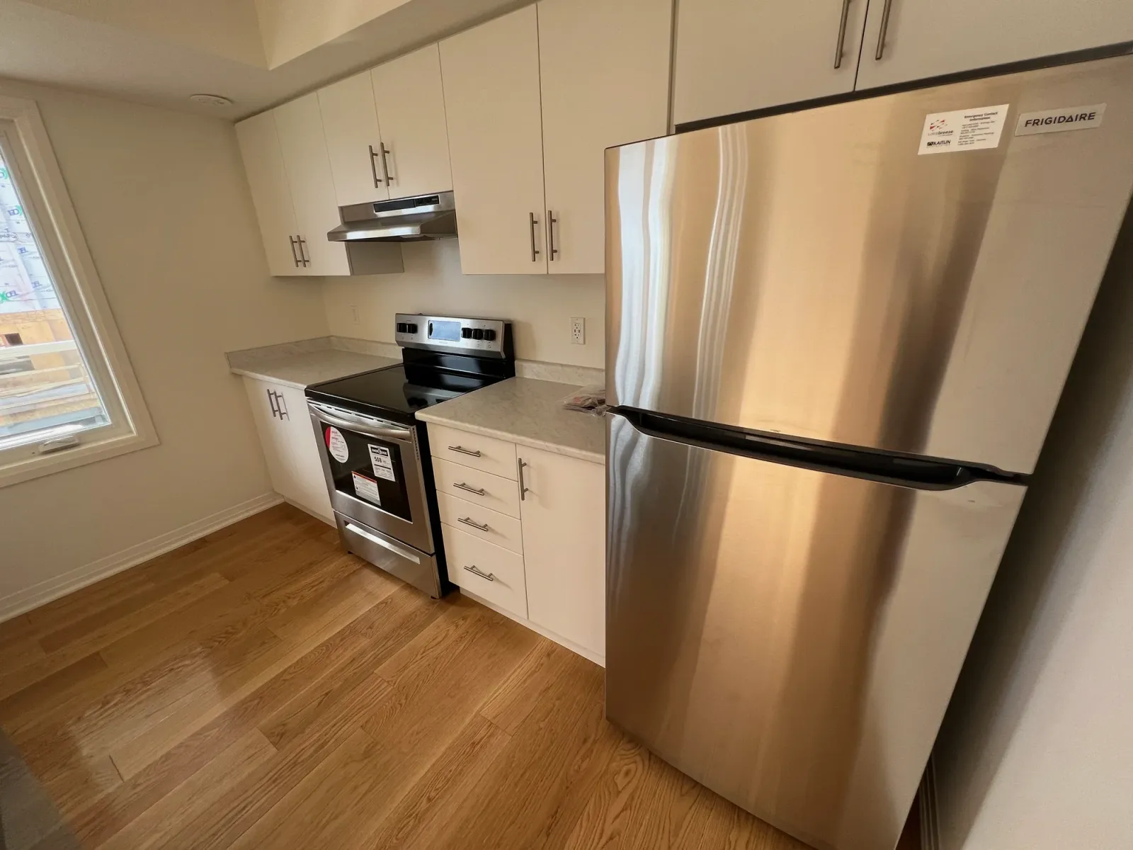White shaker kitchen with light wood floors and stainless steel appliances after residential cleaning