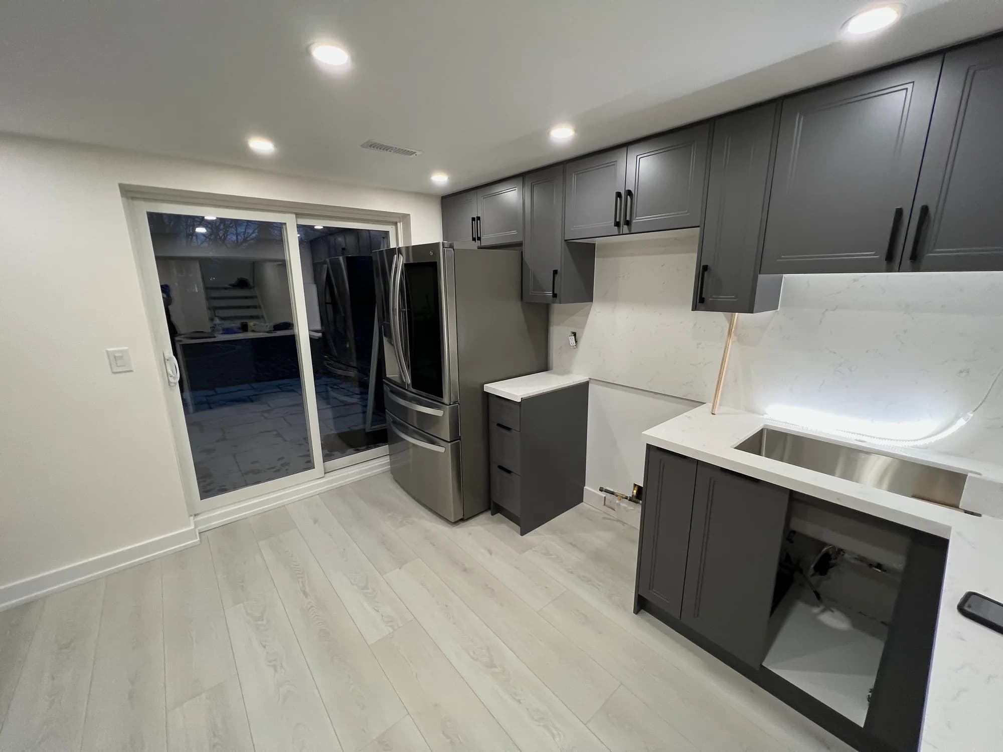 Gray cabinet kitchen with white marble counters, French-door refrigerator, and refreshed surfaces after cleaning