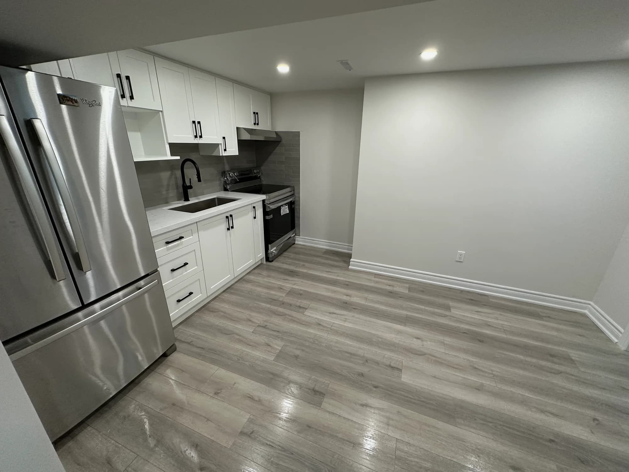 Bright white kitchen with gray subway tile backsplash and stainless steel appliances after residential cleaning