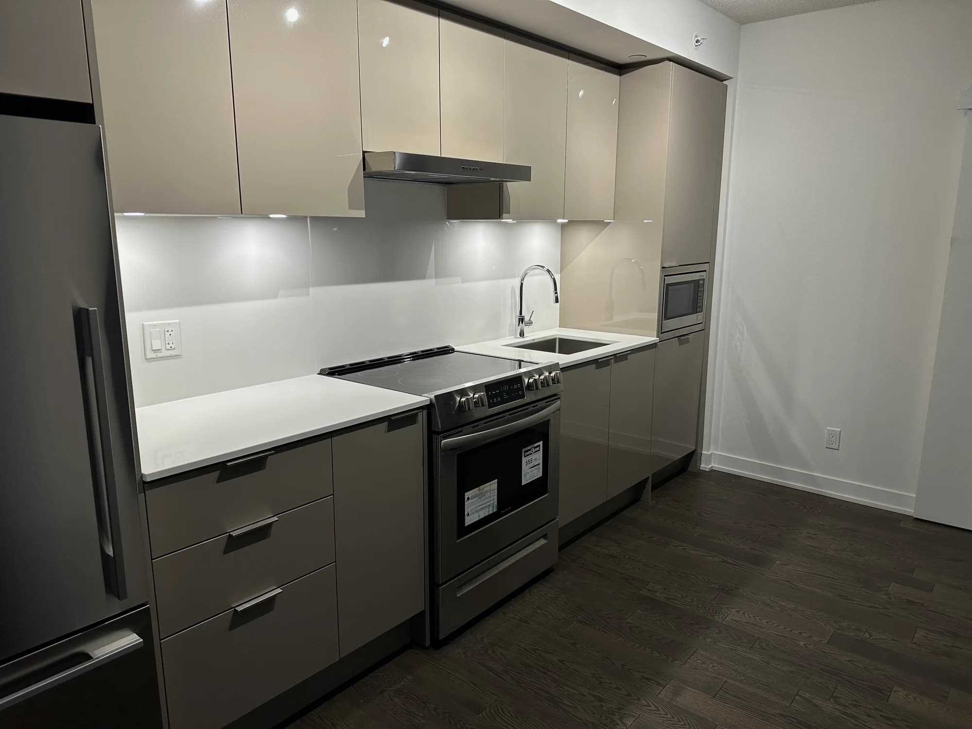 Two-tone kitchen with white upper cabinets, dark lower cabinetry, and glossy backsplash after cleaning