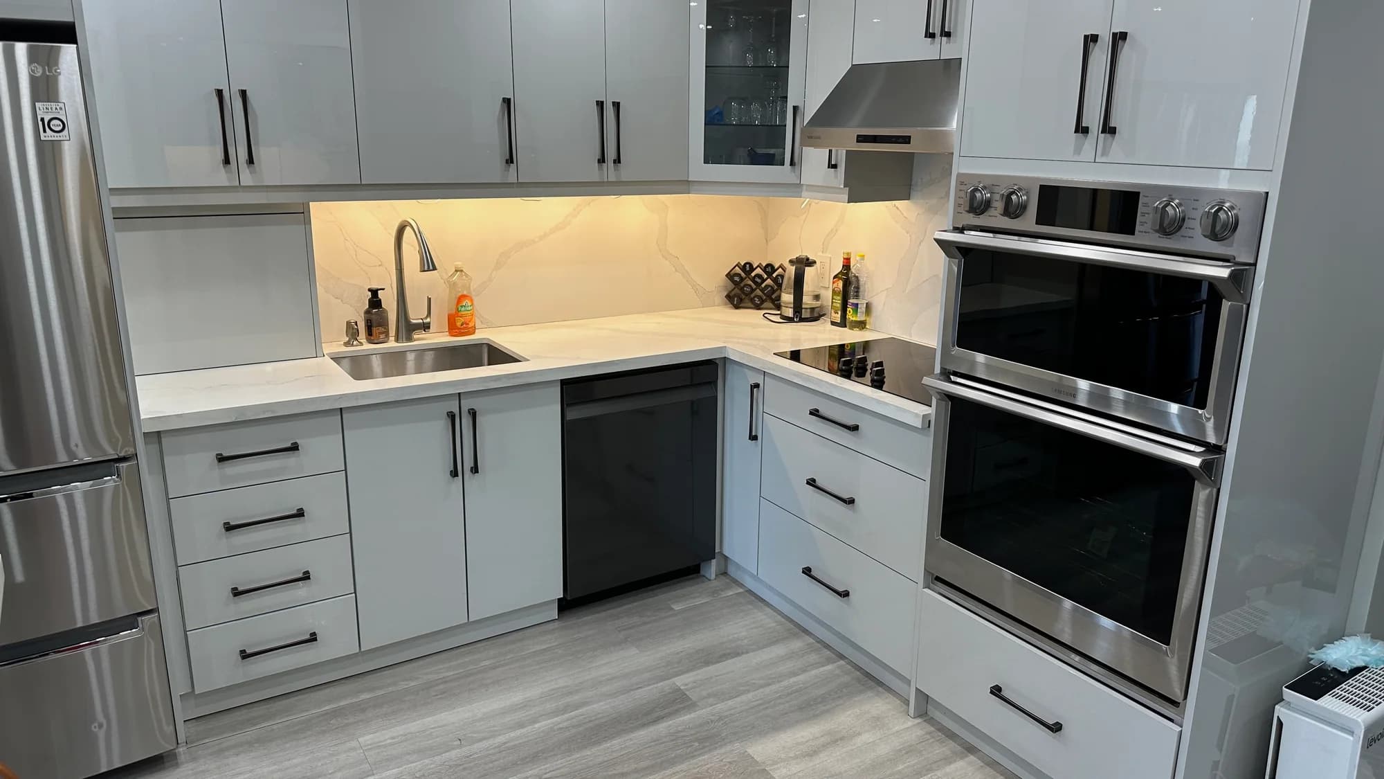 Luxury white kitchen with marble countertops and stainless steel double oven after cleaning