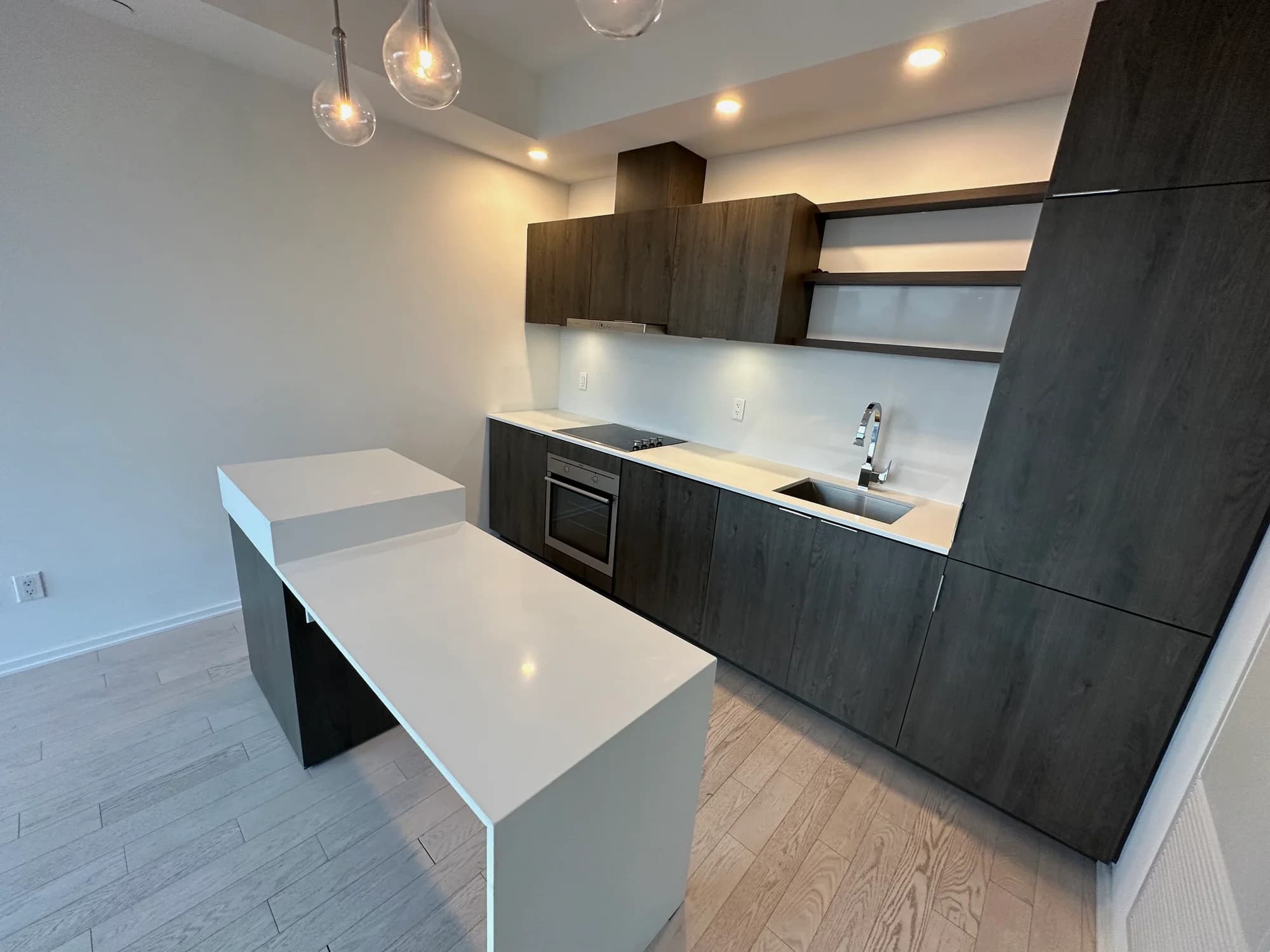 Modern kitchen with dark wood cabinetry, white island, and glass pendant lighting after deep cleaning